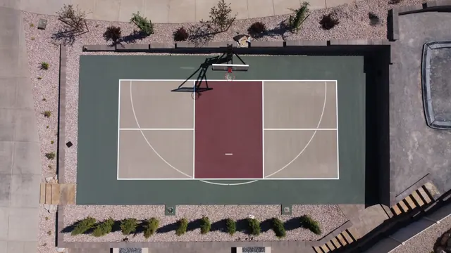 Backyard basketball court with tan playing areas, a burgundy center and dark green border.