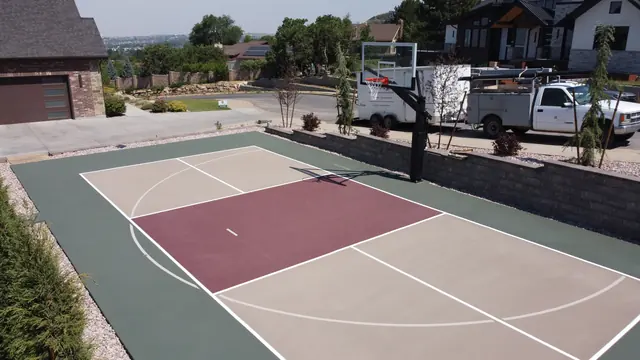 Backyard basketball court with tan playing areas, a burgundy center and dark green border.