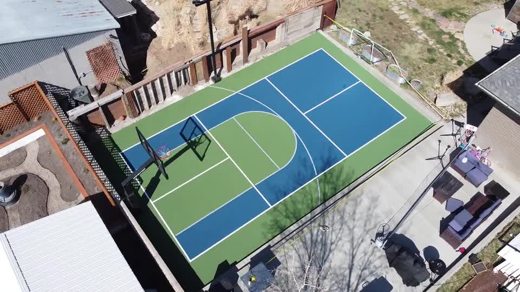 An aerial look at a fenced blue and green multi-sport court.