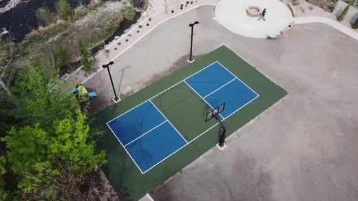 An aerial view of a blue and green shared court with a basketball hoop.