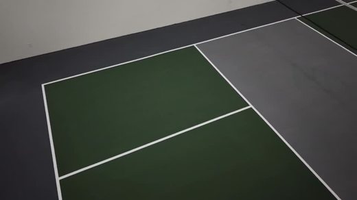 A closer aerial look at a green playing area, gray surround, and crisp white court lines.