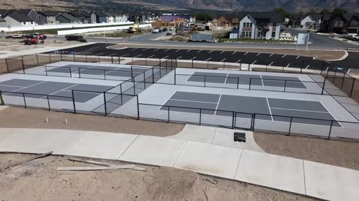 An angled aerial view of the completed fenced pickleball court complex.