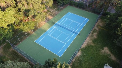 Fenced blue and green multi-sport court with basketball and pickleball lines.