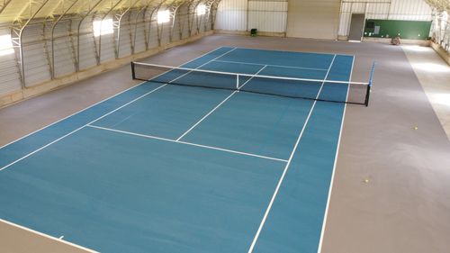 Indoor blue pickleball court with white lines and a center net.