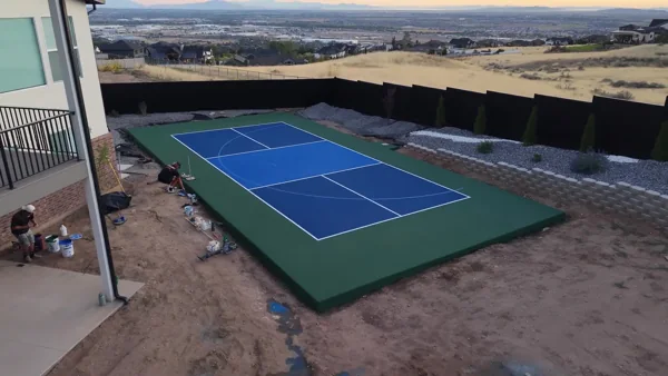 A short aerial pullback reveals the blue and green backyard court beside the home.