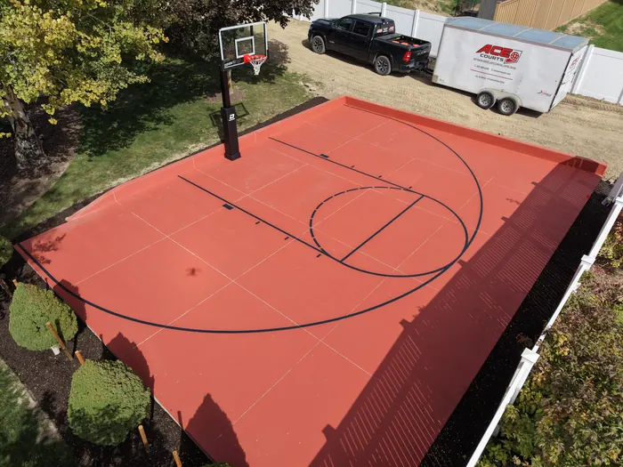 Close aerial view of the red court surface, black basketball markings and installed hoop