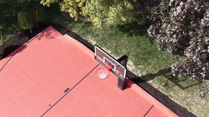 A closer aerial orbit shows the Dominator basketball hoop, red court surface, and black playing lines.