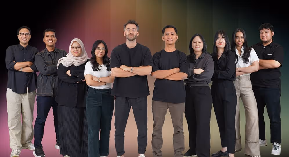 Group of ten diverse young adults standing side by side with arms crossed in front of a gradient background.