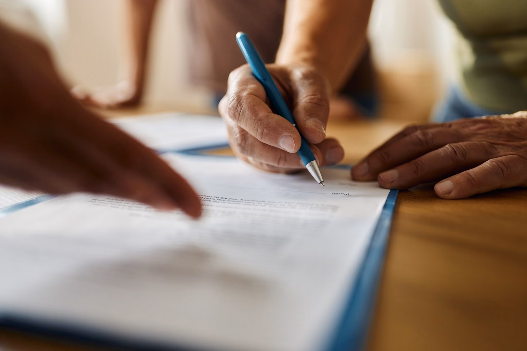 Older hands signing a contract at a table