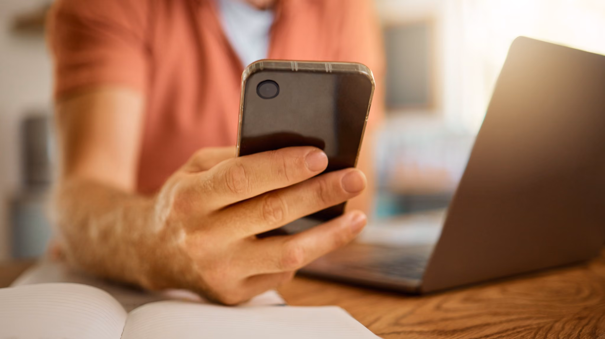 Man using a phone beside a laptop while working from home