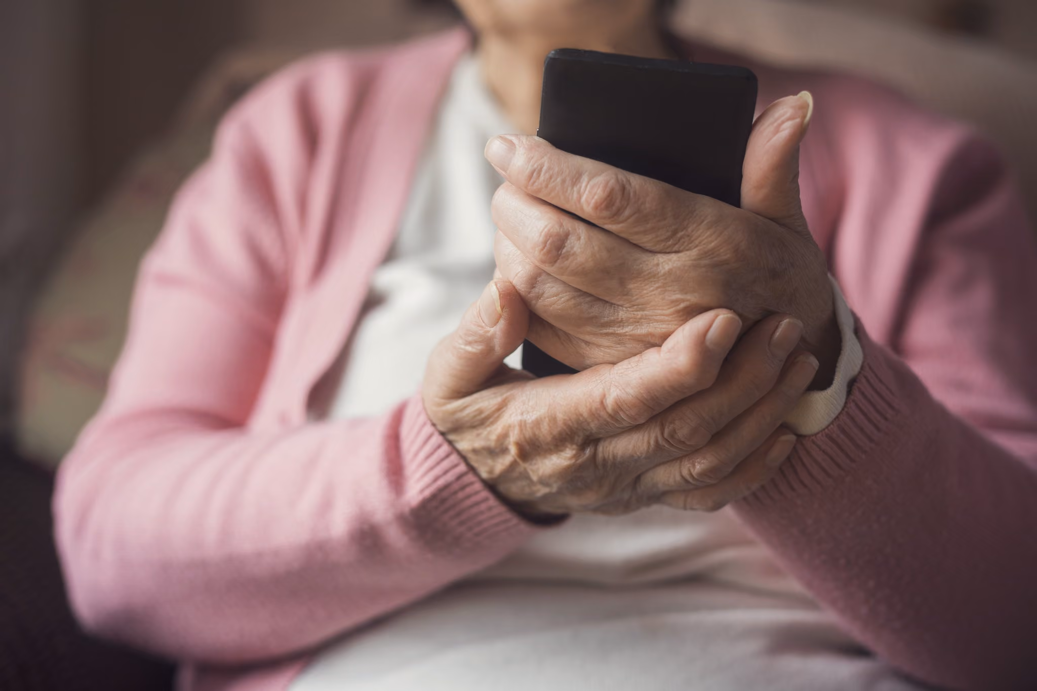 Senior woman sitting at home holding a phone