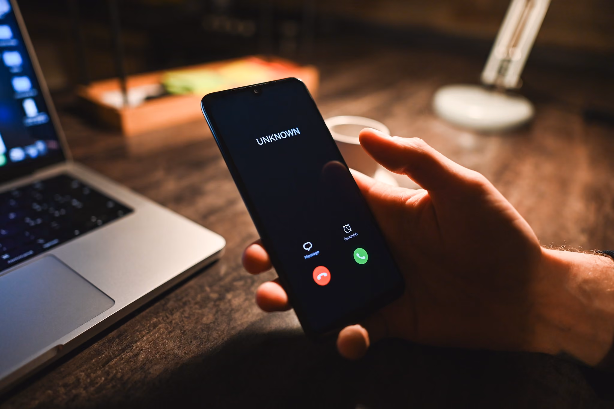 Smartphone showing an unknown incoming call beside a laptop
