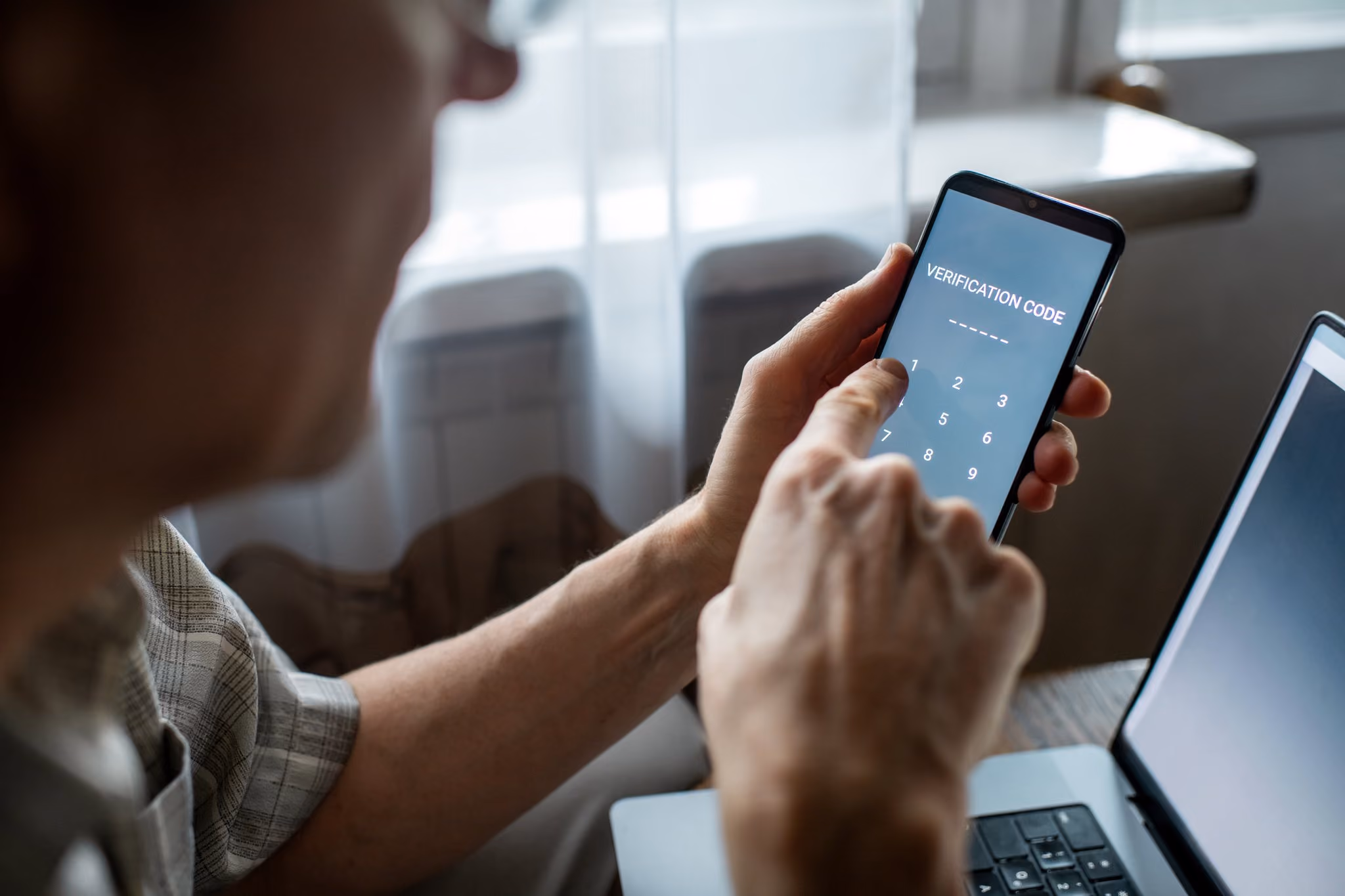 Senior man entering a verification code at home
