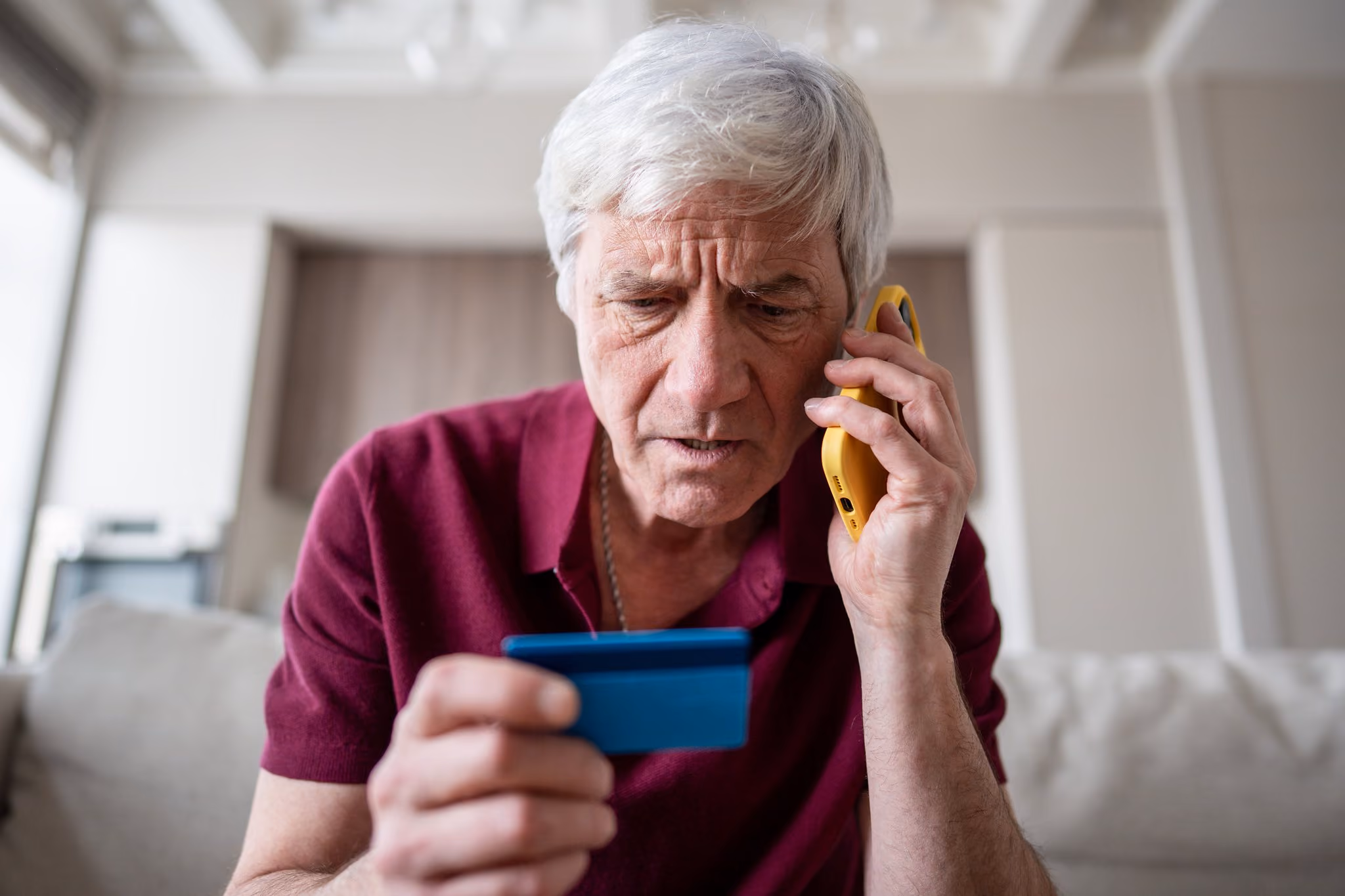 Pensioner holding a bank card while on the phone