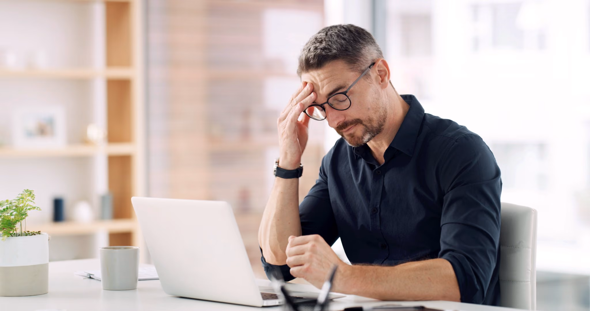 Man sitting at a laptop with his head in his hand