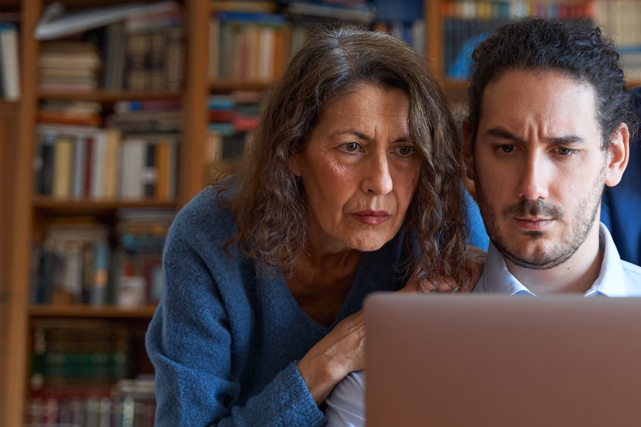 Adult son helping his mother review finances on a laptop