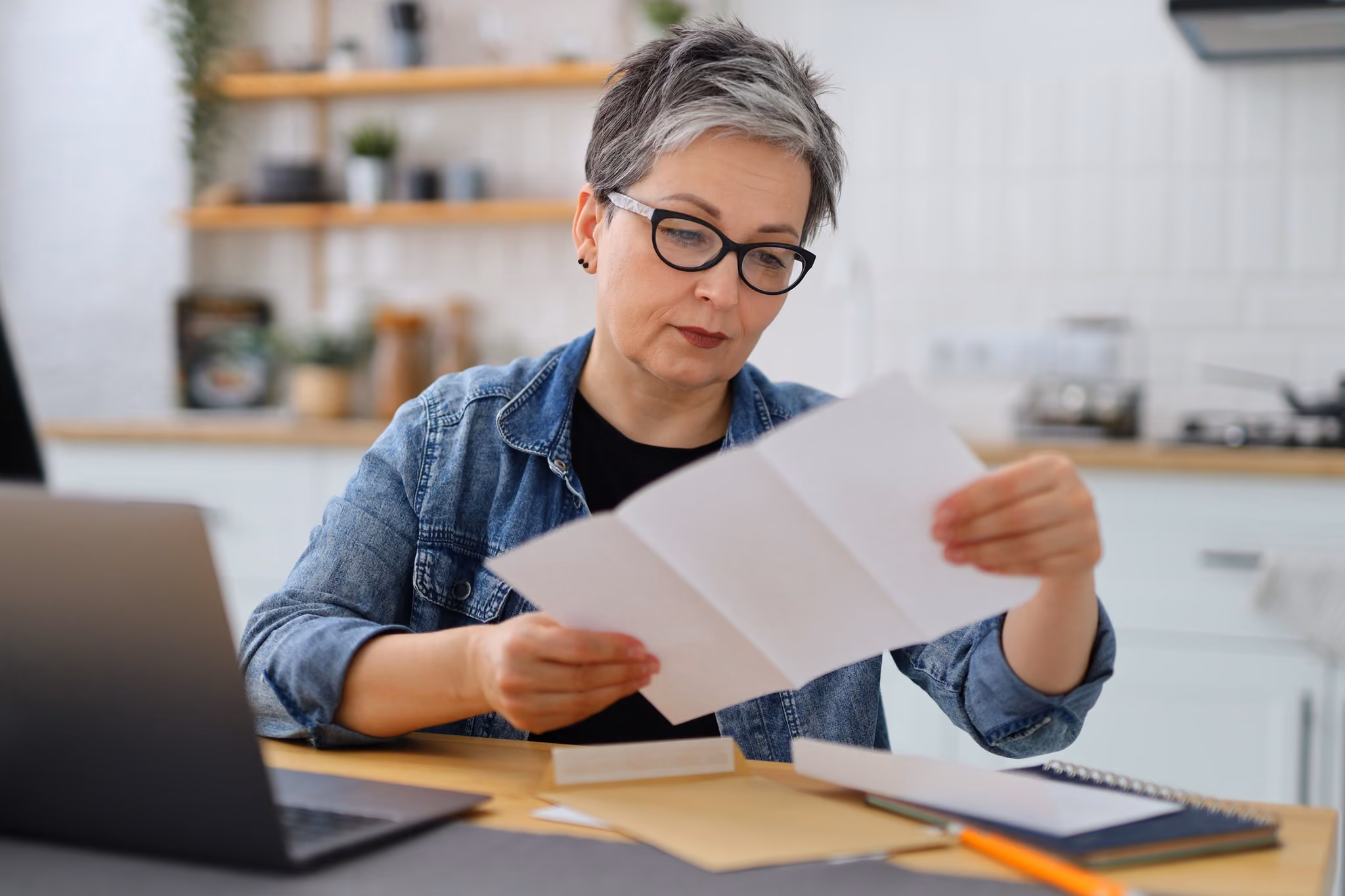 Woman reading a letter at her kitchen table