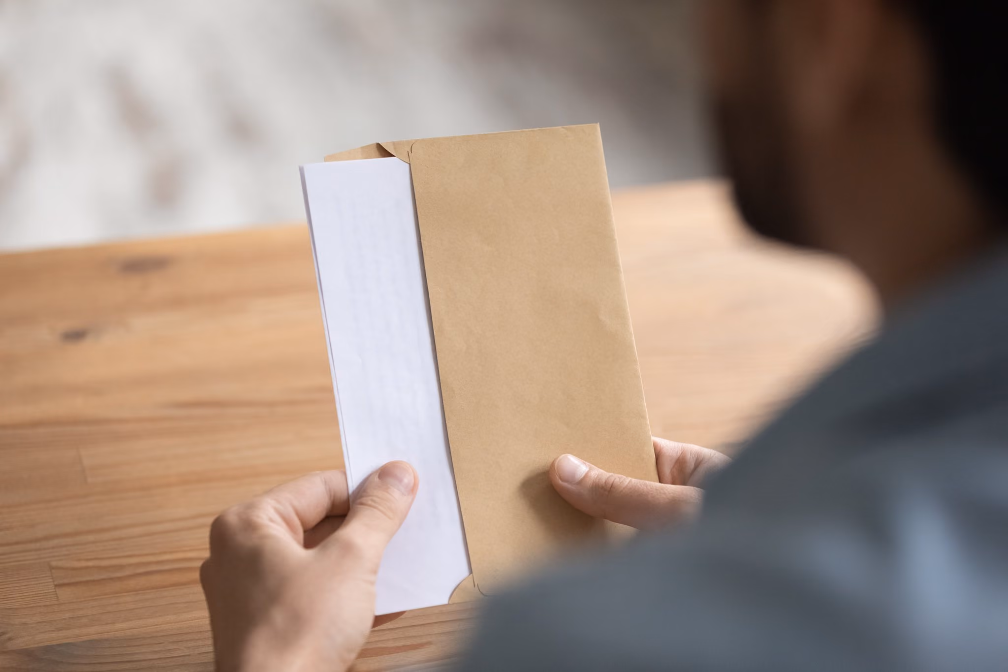 Hands opening a brown envelope at a table