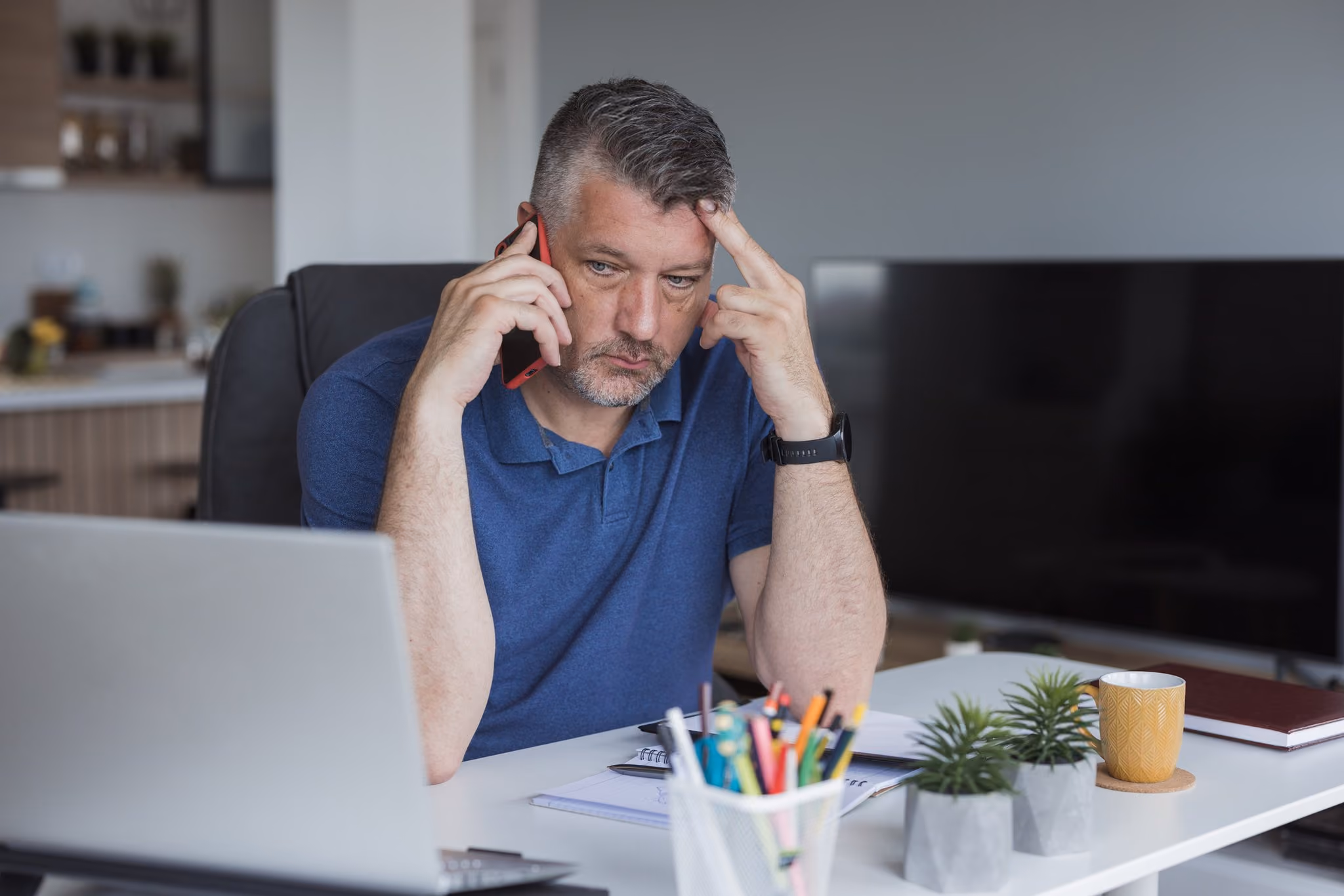 Stressed man on a phone call at his work desk