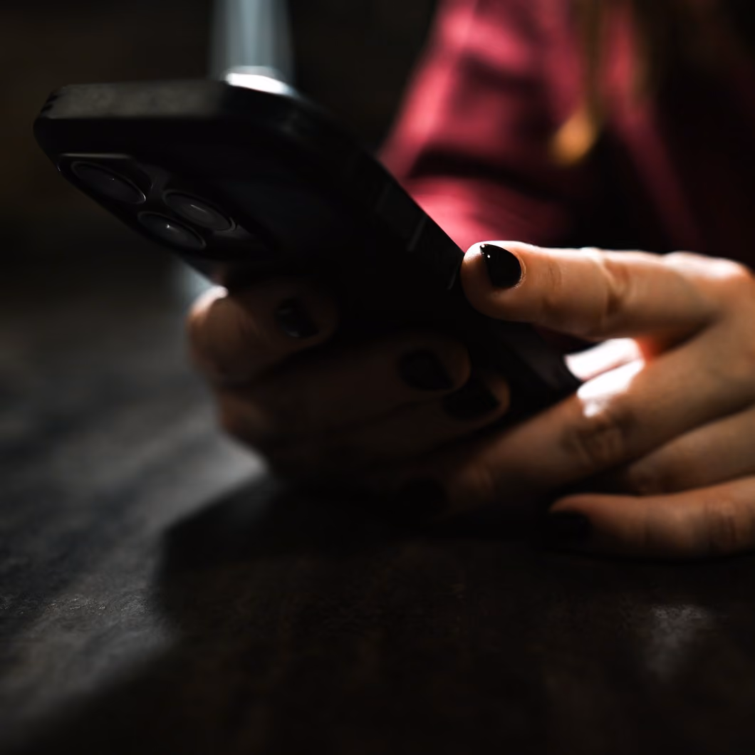 Woman's hands holding a smartphone in a dimly lit room