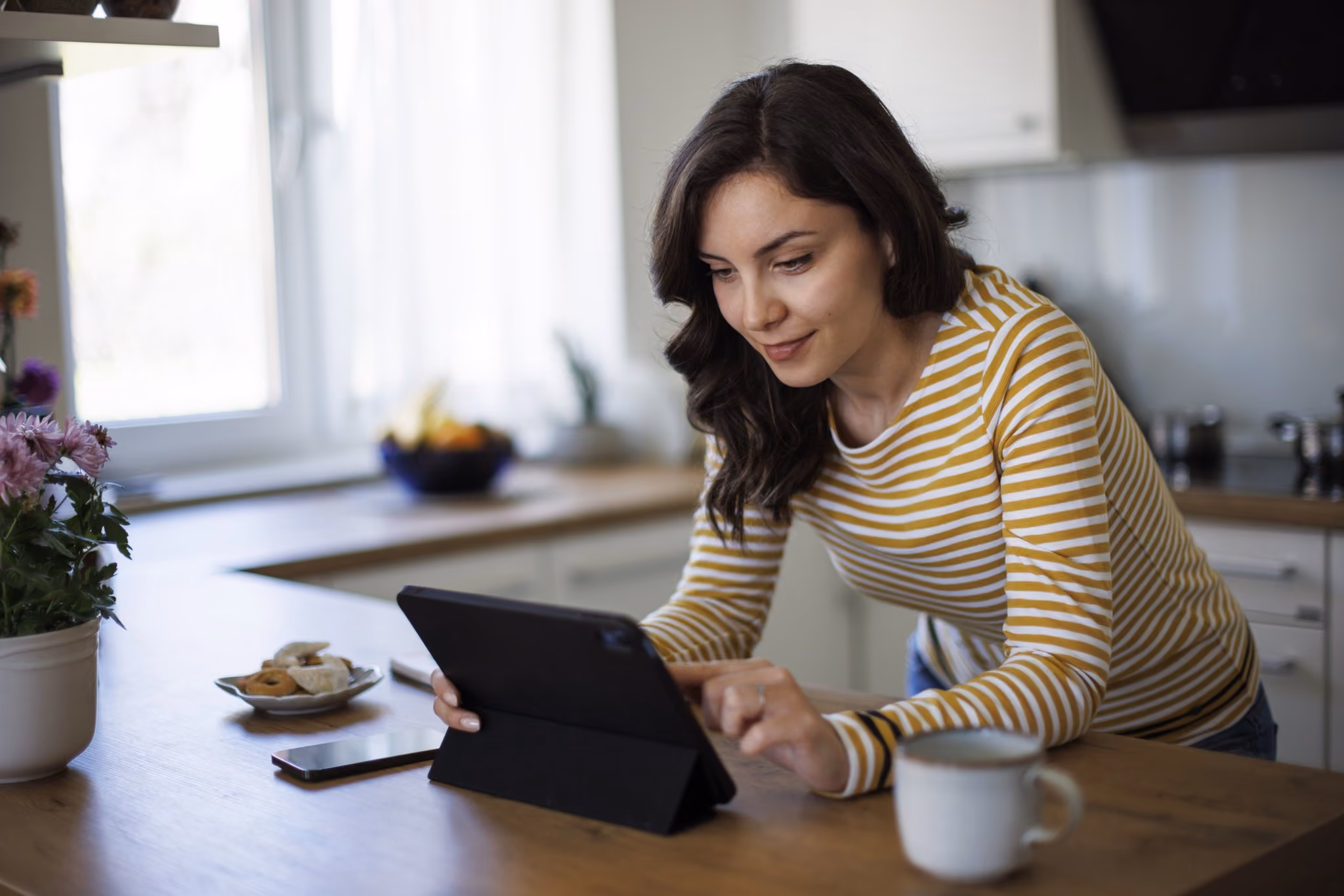 Woman at her kitchen bench reading on a tablet