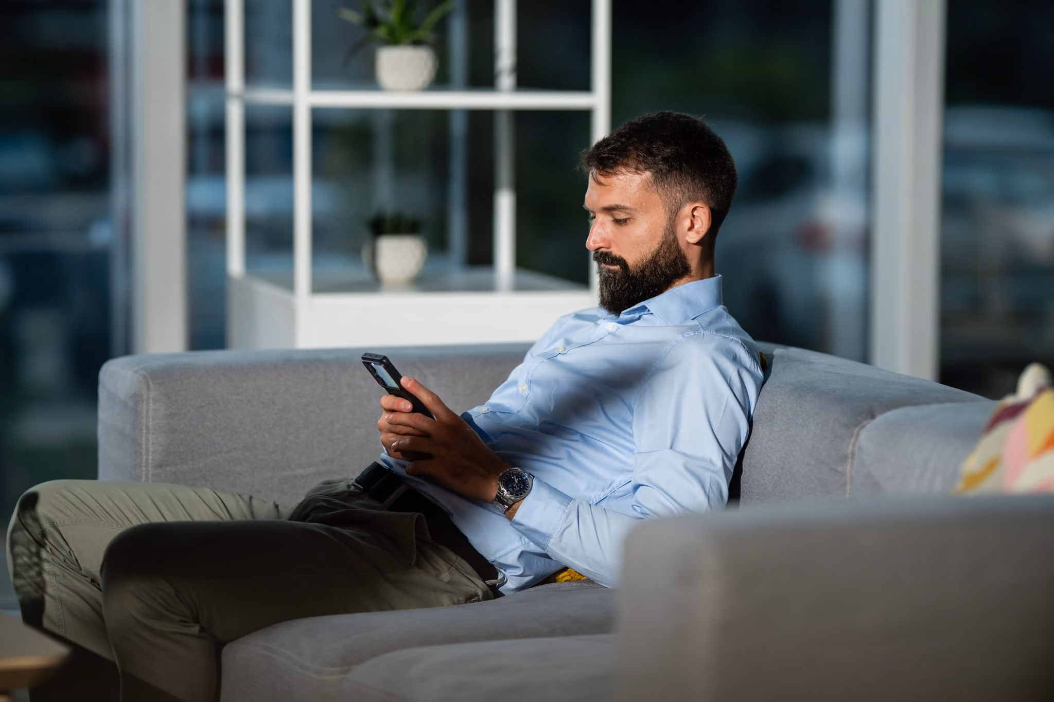 Man sitting on a sofa reading on his phone