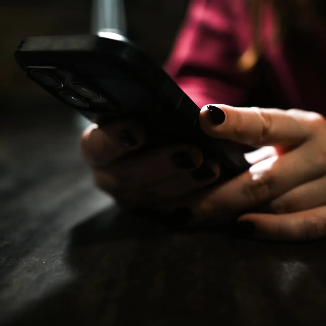 Woman's hands holding a smartphone in a dimly lit room