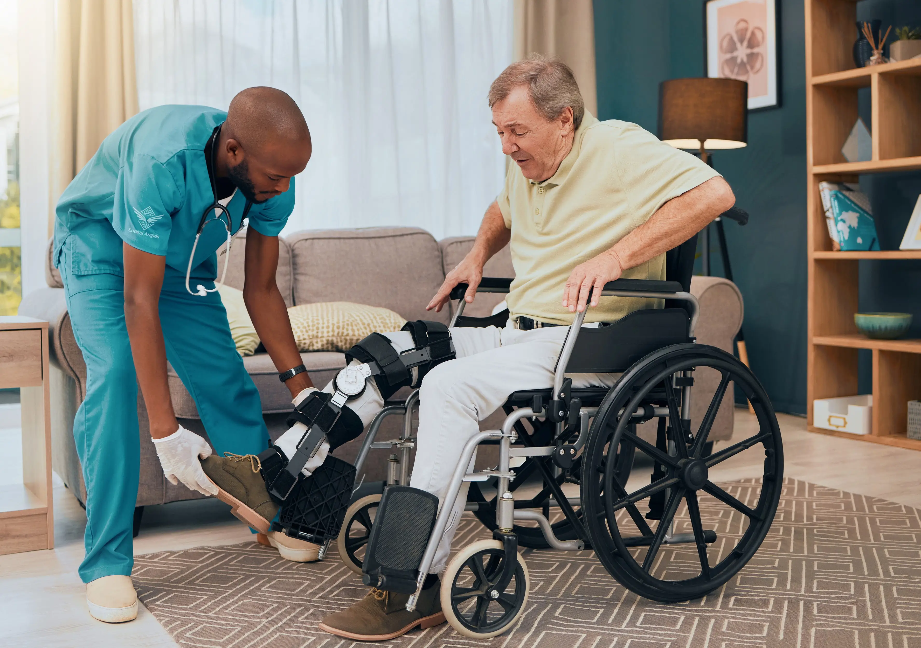 Healthcare worker fitting a leg brace on a senior man sitting in a wheelchair in a living room.