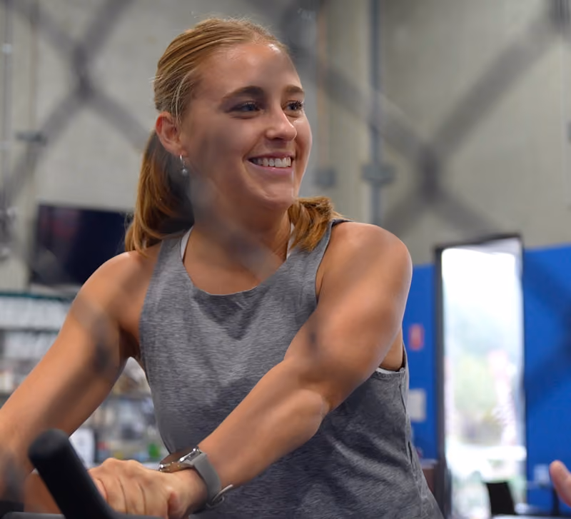 sepsa client smiling while riding a bike in gym