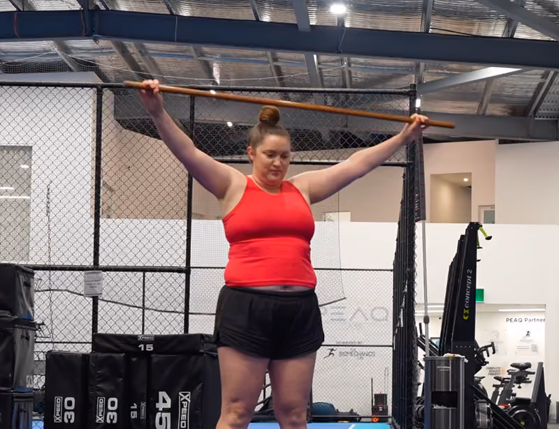 client working on shoulder rehab with stick overhead