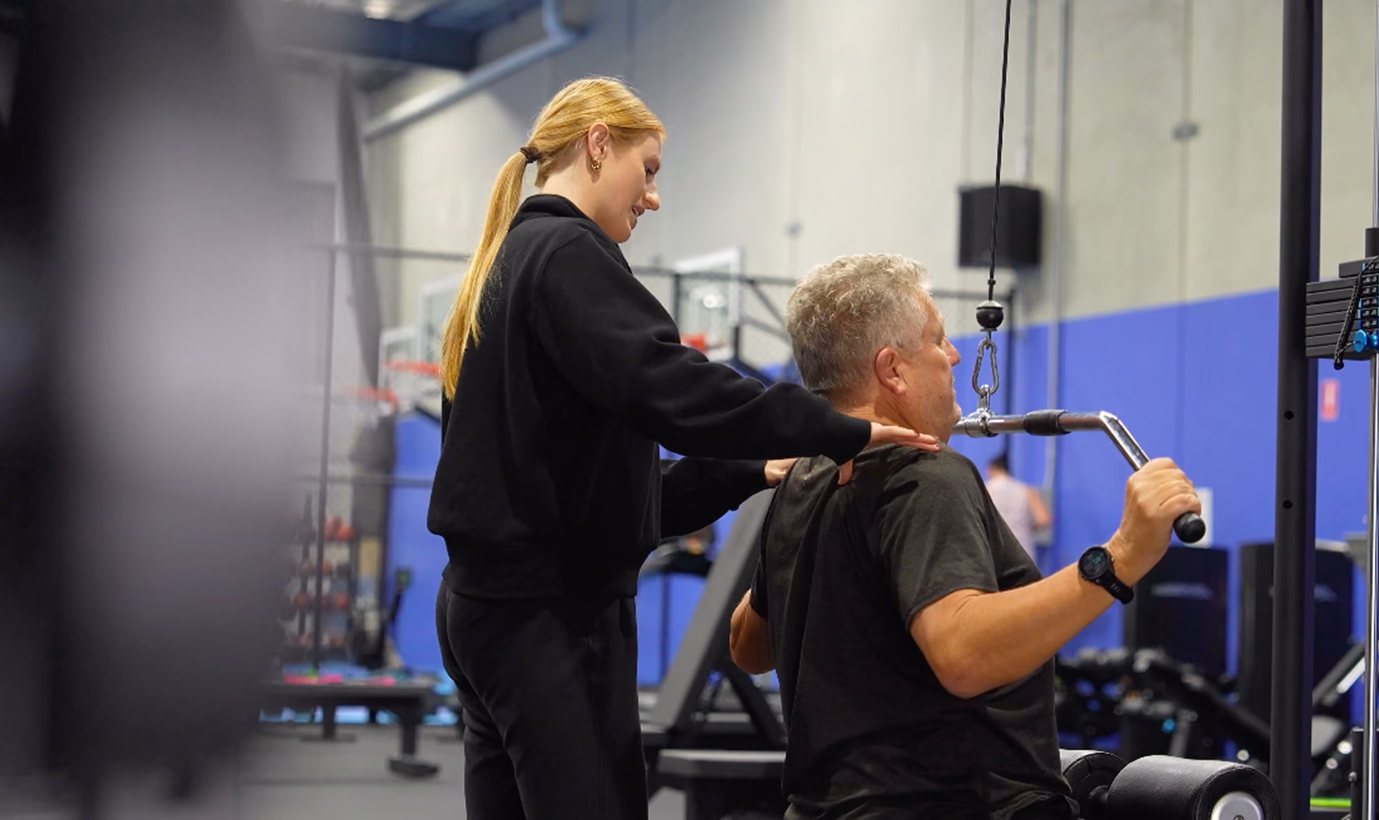 chantel helping client with shoulder press at peaq gym