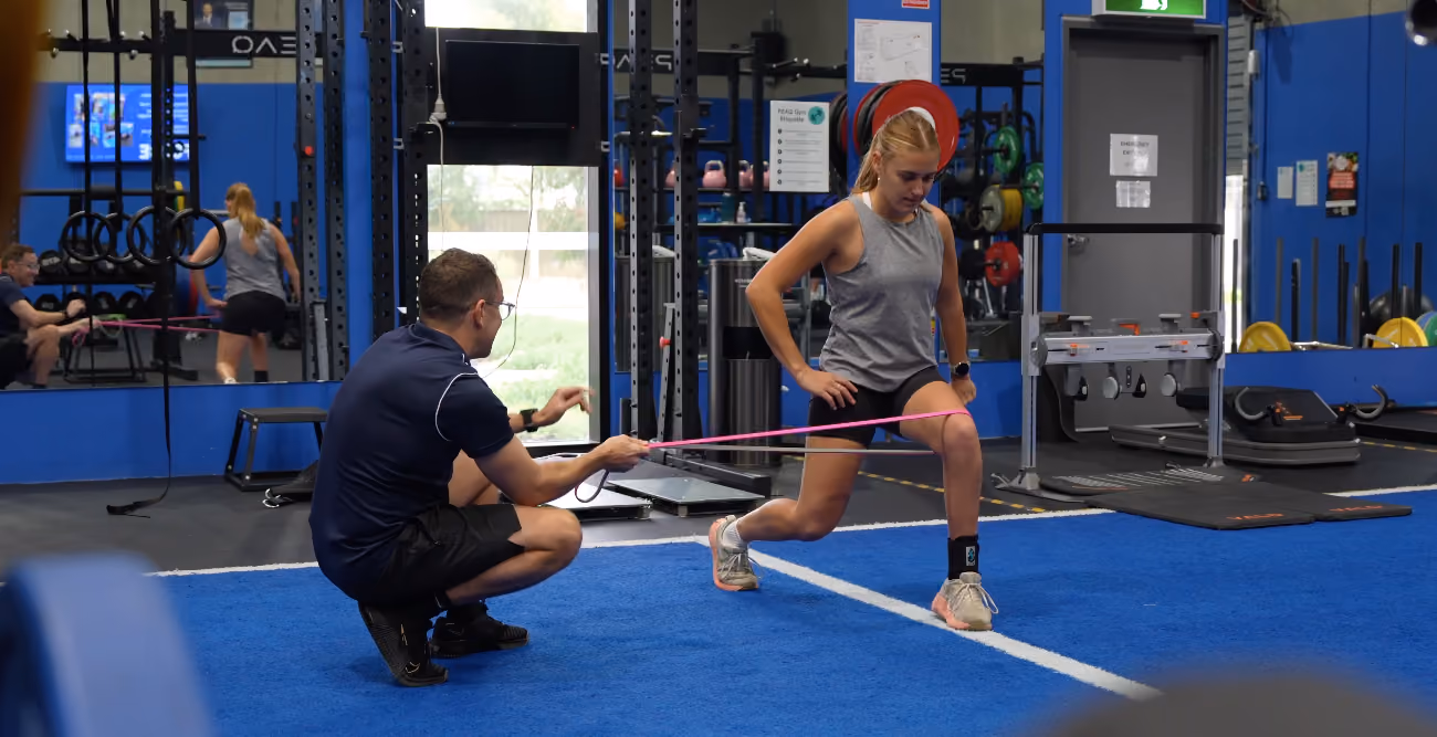 Exercise physiologist Chris coaching an athlete through an exercise in the gym