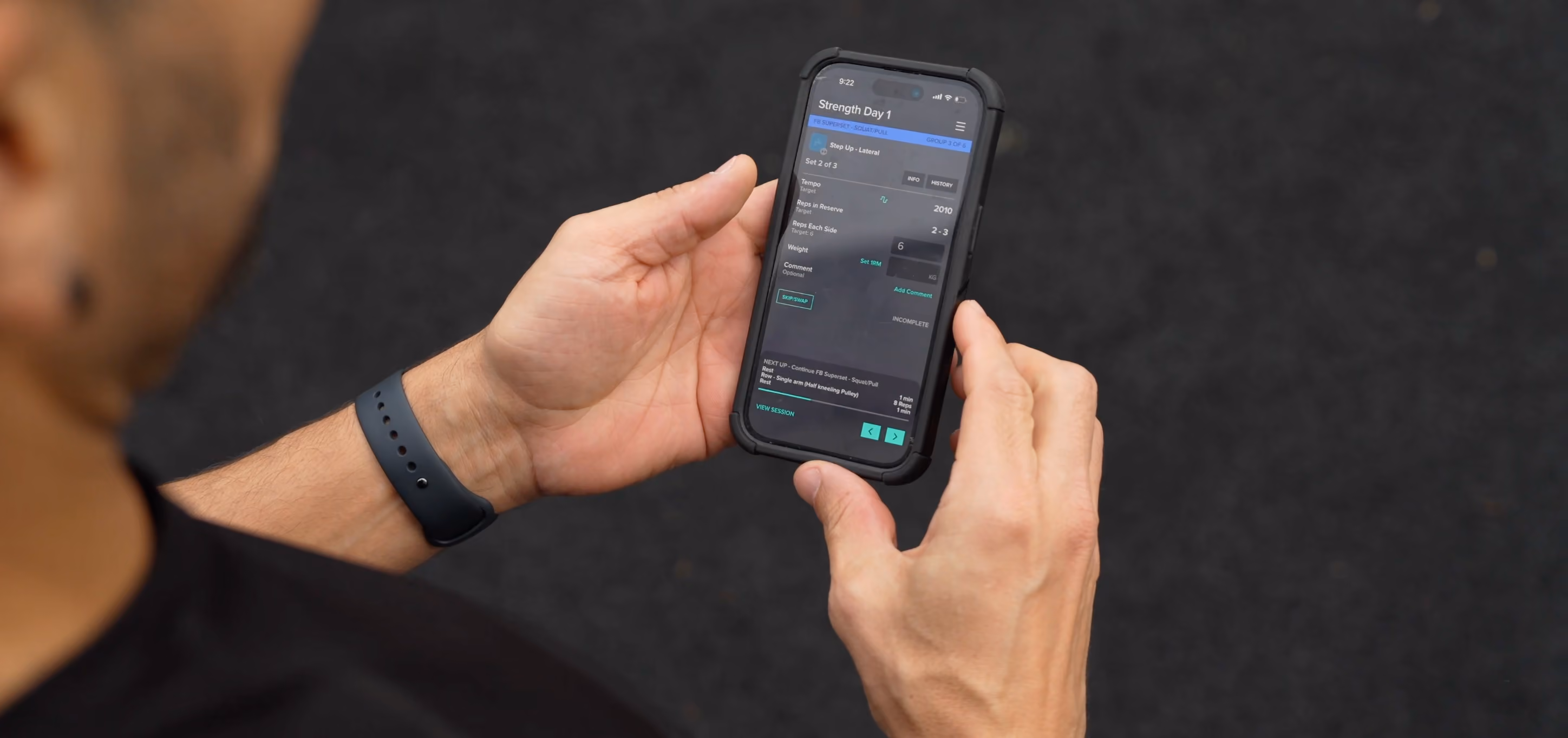 Person holding phone displaying Strength Day 1 workout details on a fitness app.