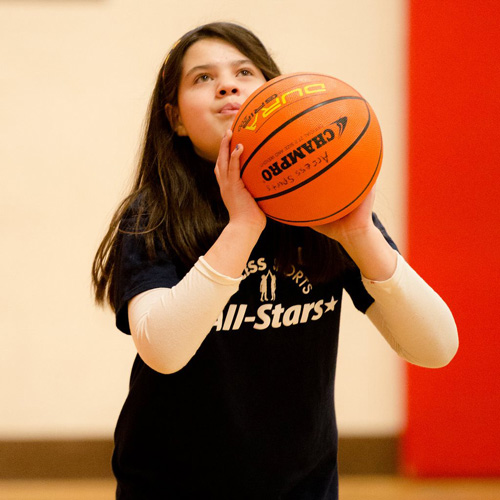 A girl playing basketball and is about to score