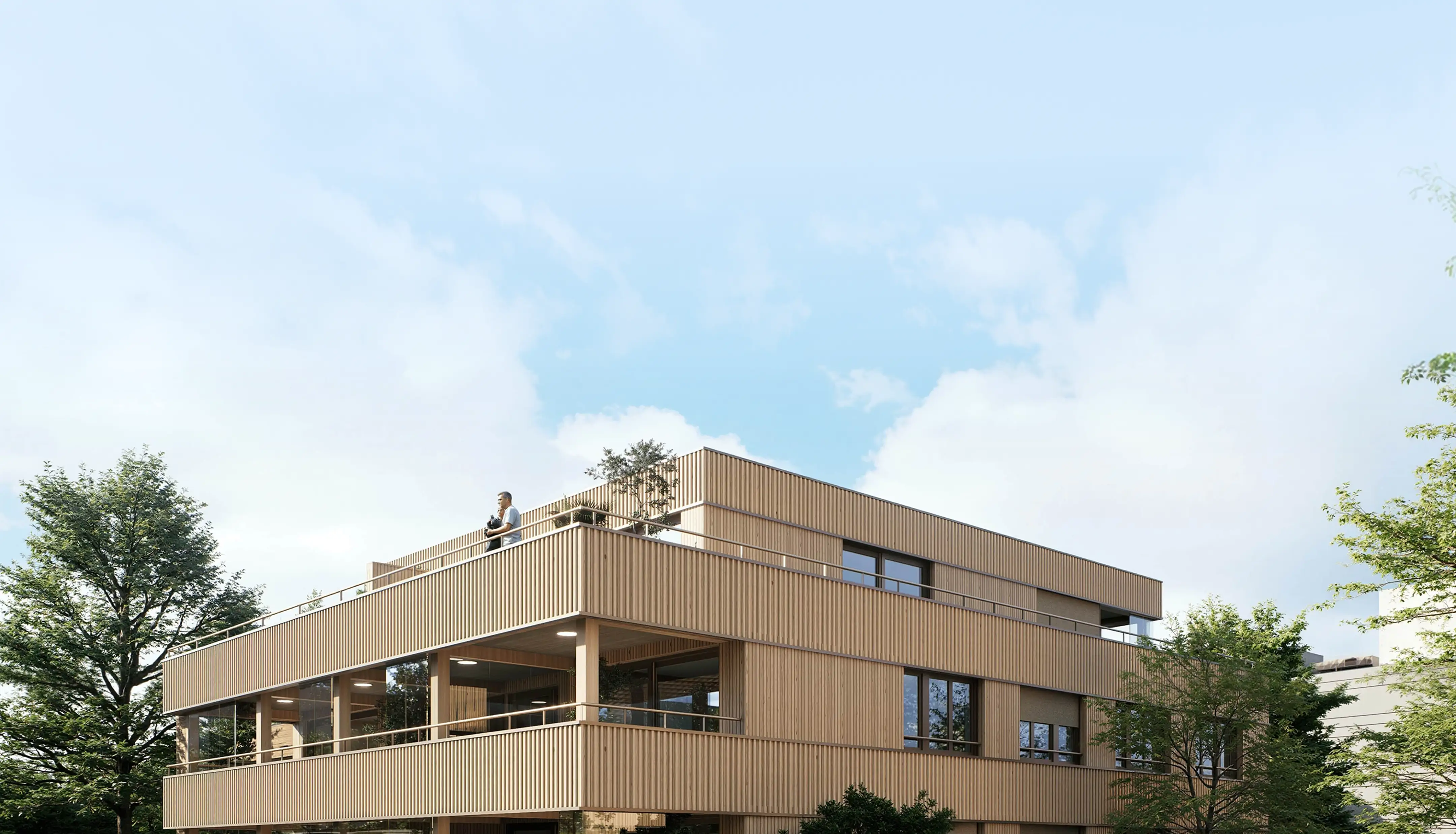Modern two-story wooden building with large windows and a person standing on the rooftop terrace.