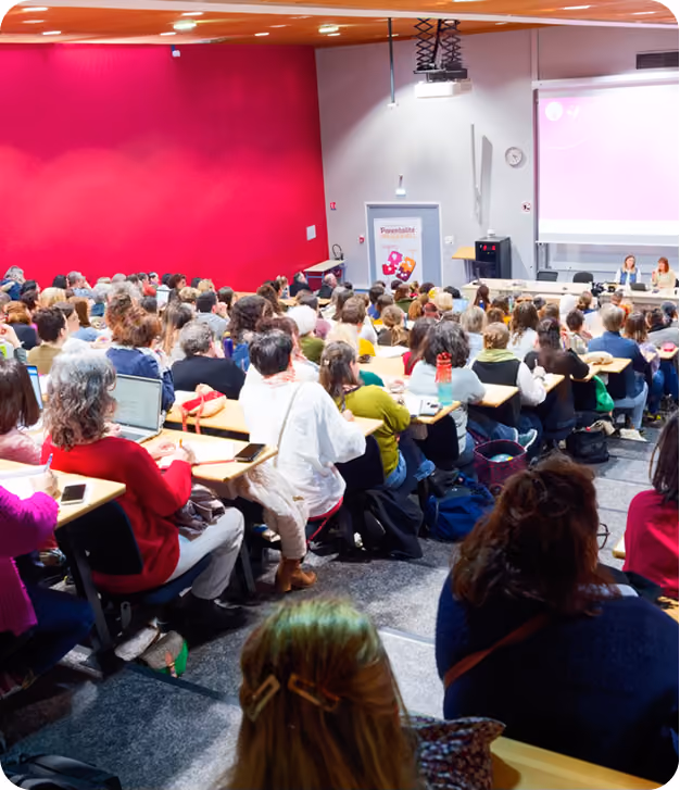 Salle de conférence remplie de personnes assistant à une présentation projetée en classe.