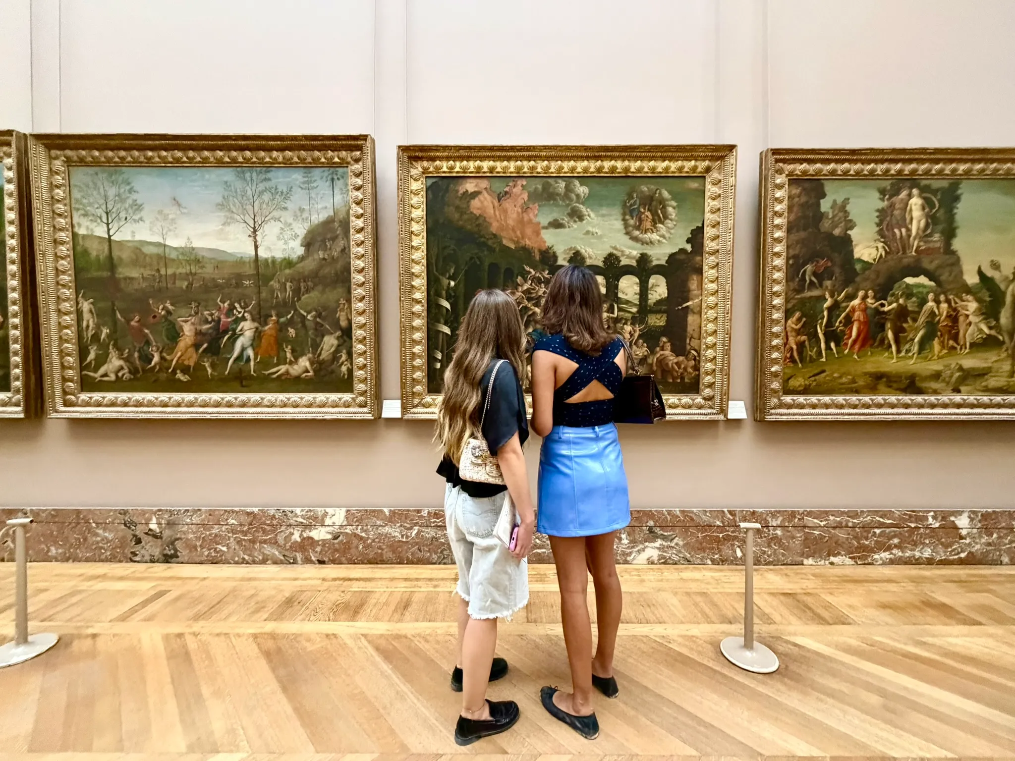 Two visitors looking at paintings in a museum gallery