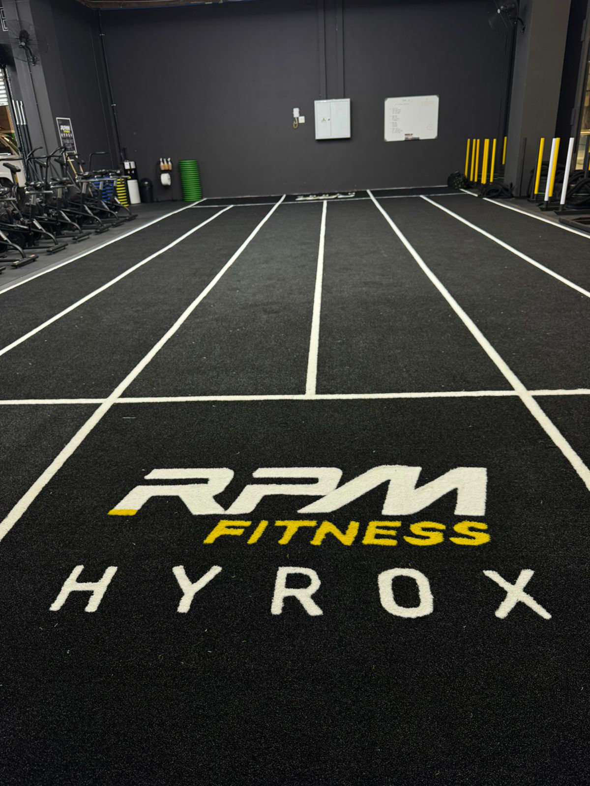 Modern gym interior with weight racks, exercise bikes, large windows, and logos of Red Bull and Nike.