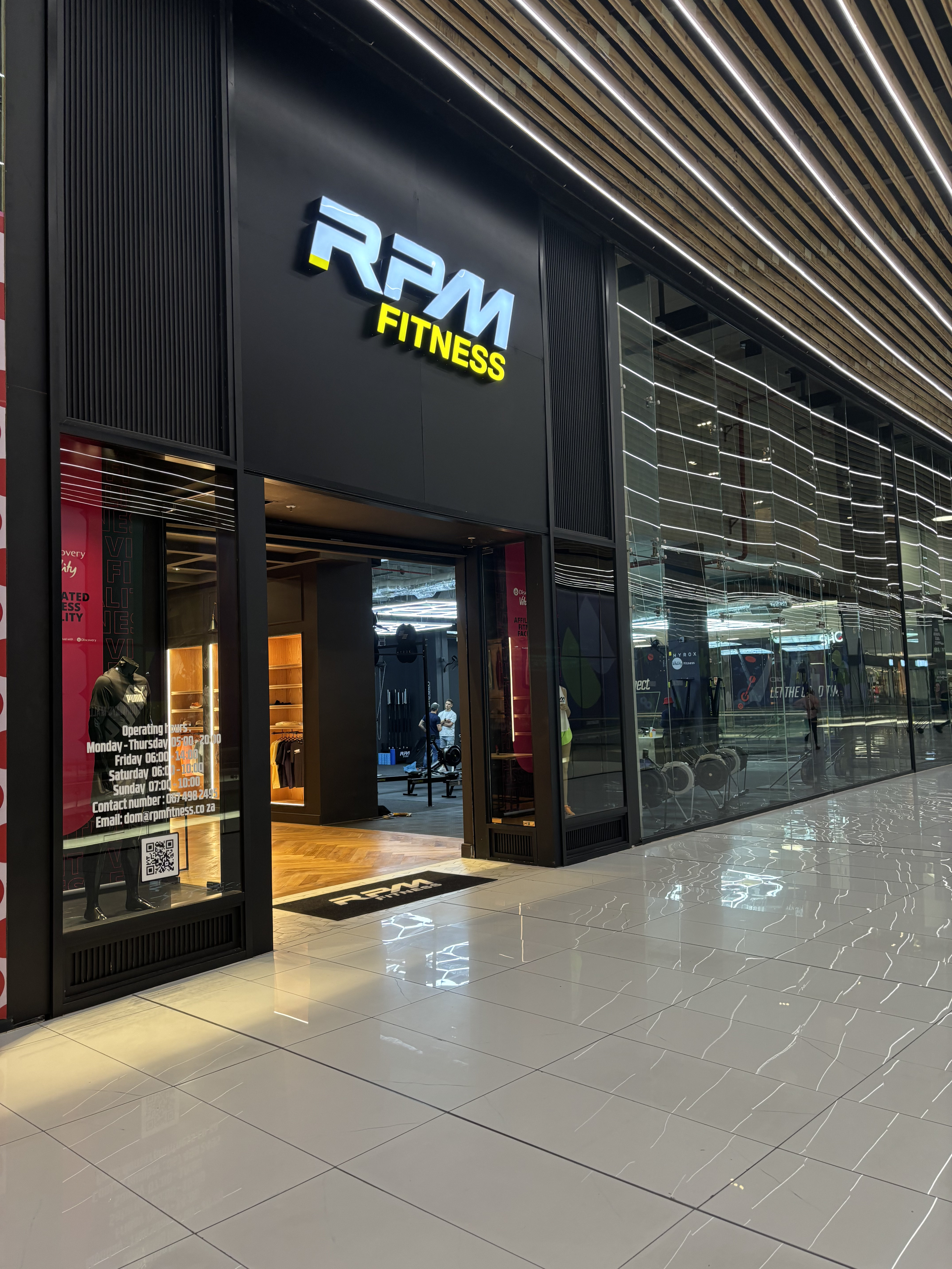 Modern gym interior with treadmills, rowing machines, weights, and RPM Performance, Red Bull, Nike logos on floor and wall.