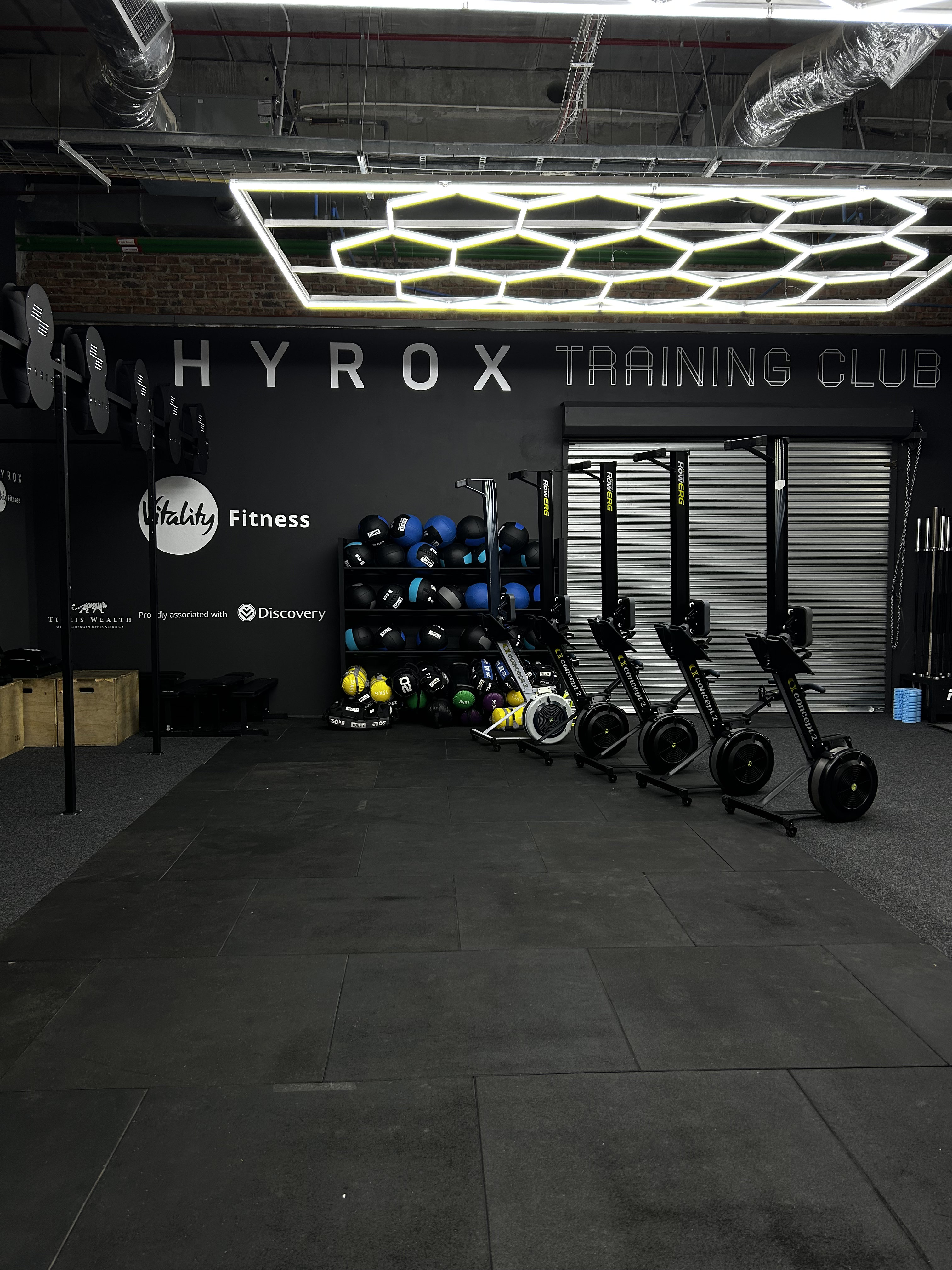 Modern gym interior with weight racks, exercise bikes, large windows, and logos of Red Bull and Nike.