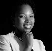 Smiling woman with braided hair posing against a black background.