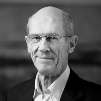 Black and white portrait of an elderly man wearing glasses and a suit jacket.