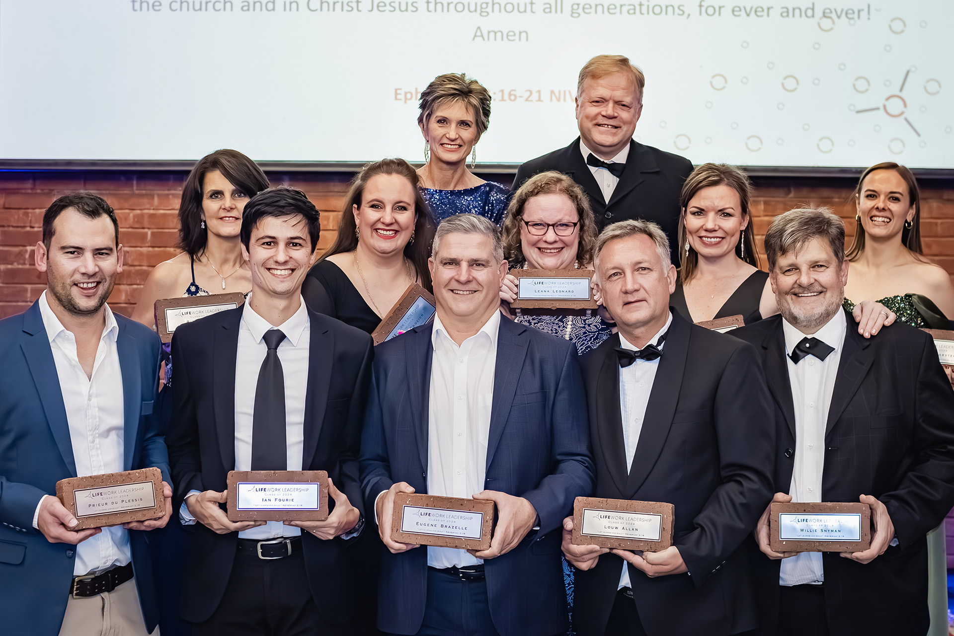 Group of men and women dressed formally holding LifeWork Leadership plaques at an award event.