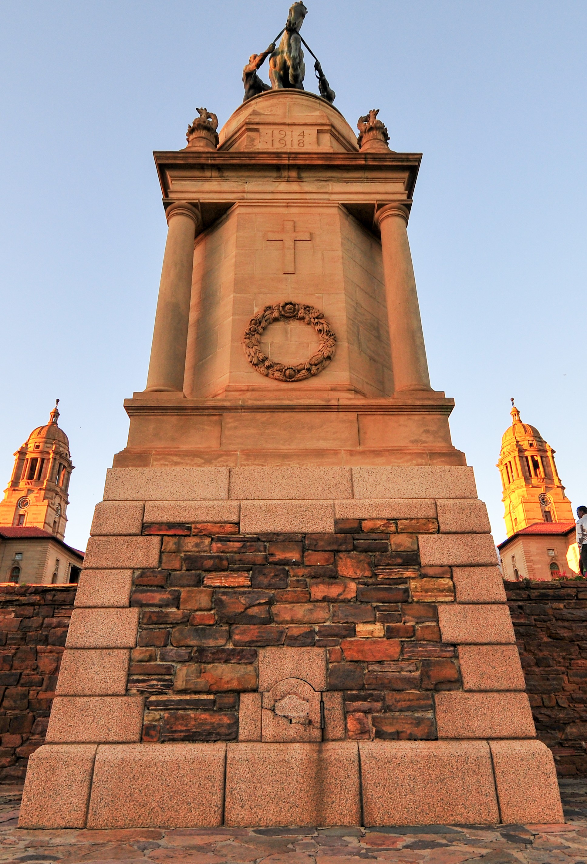 War memorial monument with a horse statue and two figures on top, showing dates 1914-1918, flanked by two domed towers.