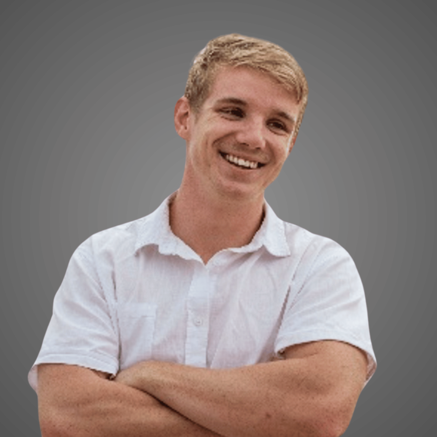 Smiling young man with folded arms wearing a white short-sleeve button-up shirt against gray background.