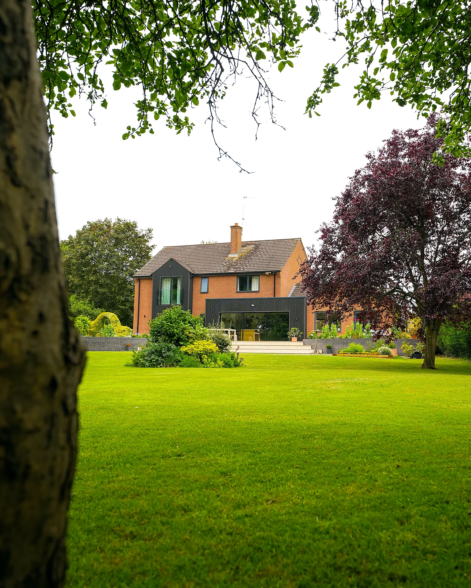 Rear garden and extended house at Water's Edge, Warwickshire