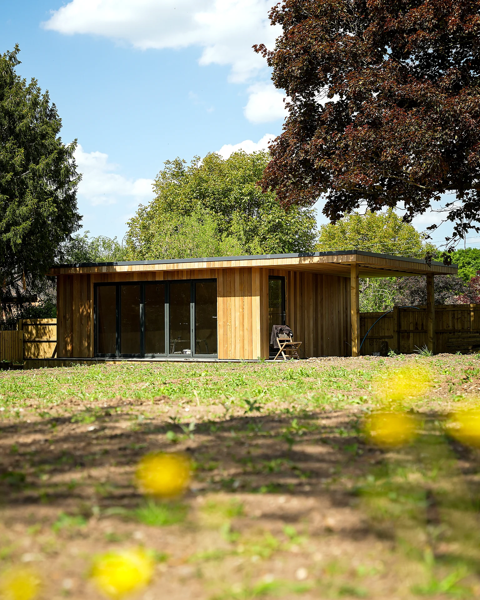 Timber-clad single-storey building with glazed doors, seen from the garden