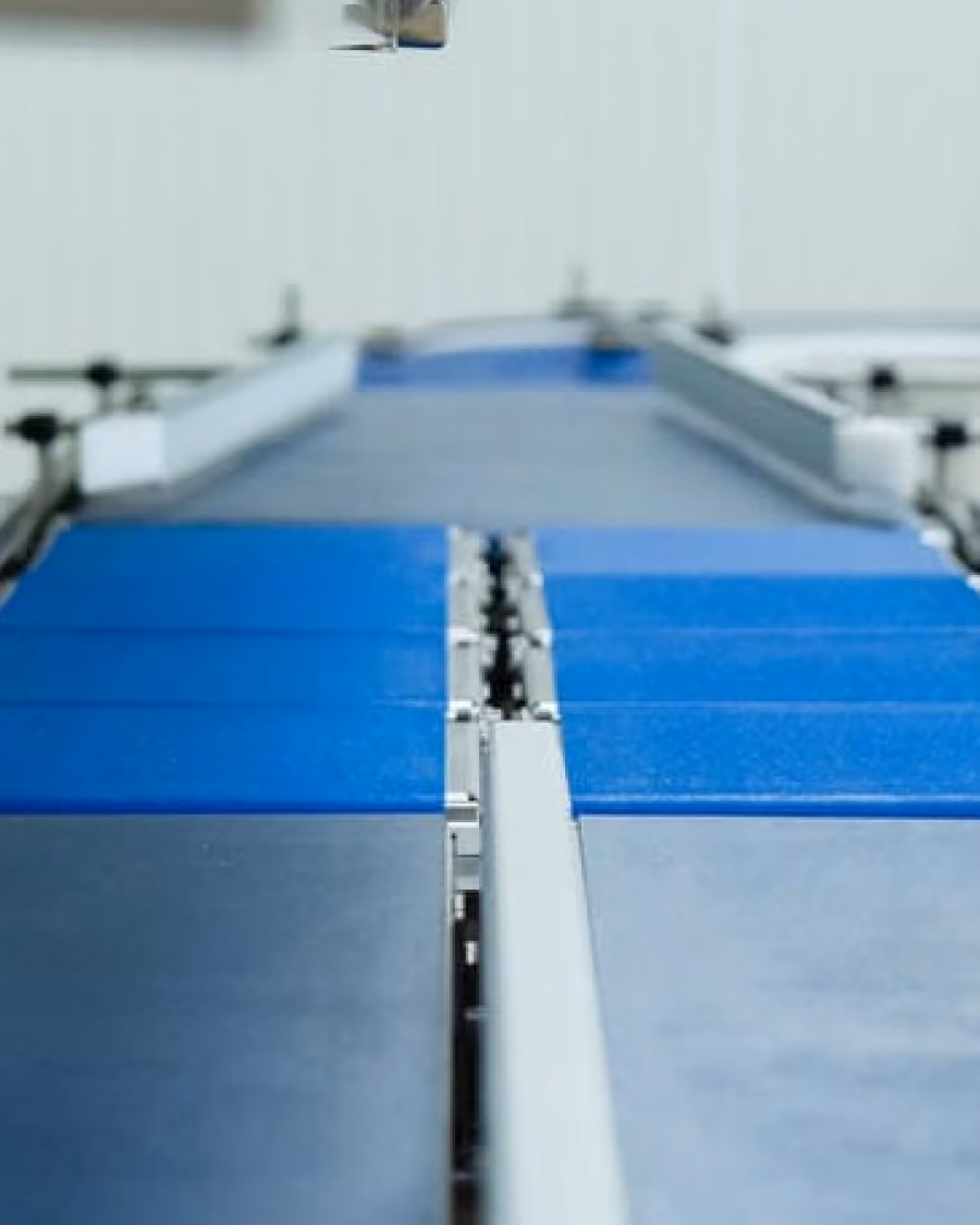 Close-up of a blue conveyor belt system in an industrial or manufacturing setting.
