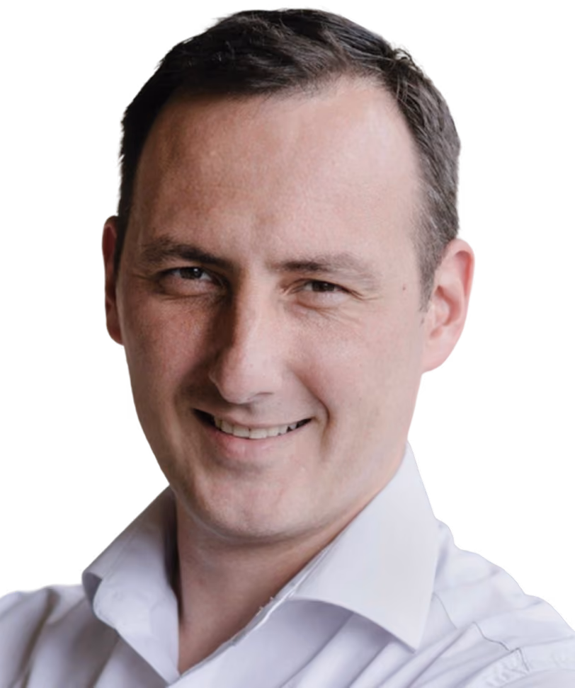 Smiling man with short brown hair wearing a white collared shirt on a black background.