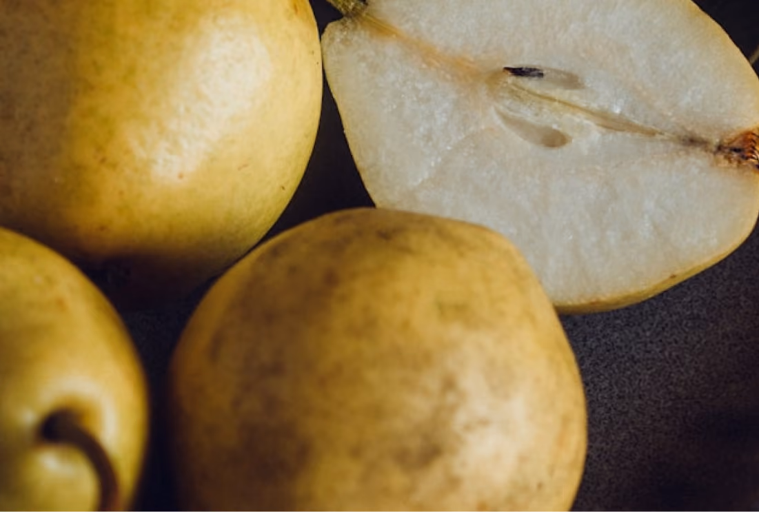 Whole and halved pears showing light brown skin and white flesh with seeds.